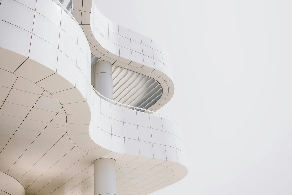 White curved facade of a modern building against a pale sky