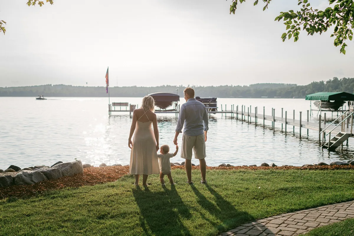 Familie mit zwei kleinen Kindern am Ufer eines Sees im Abendlicht