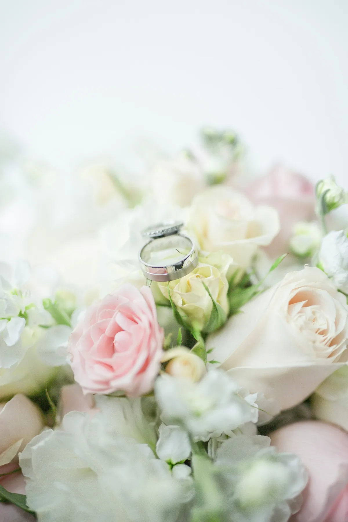 Hände eines Brautpaares auf einem weissen Brautkleid, am Finger ein Ring